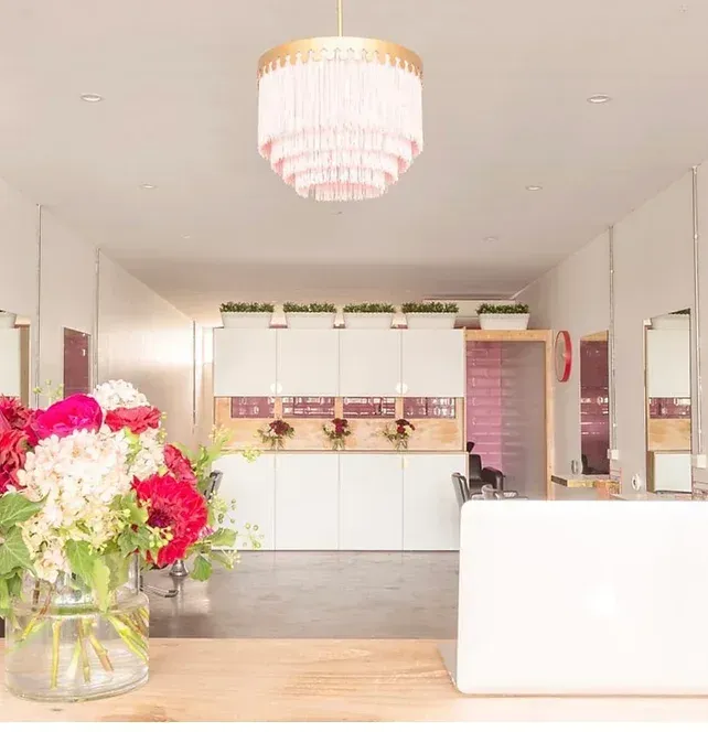 A vase of flowers sits on a table in a room with a chandelier hanging from the ceiling
