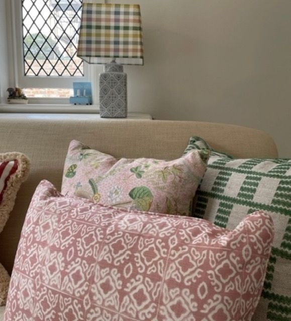 A couch with pink and green pillows and a lamp