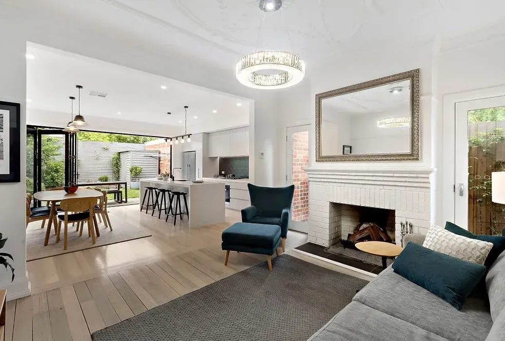 A living room with a couch, chair, table and fireplace.