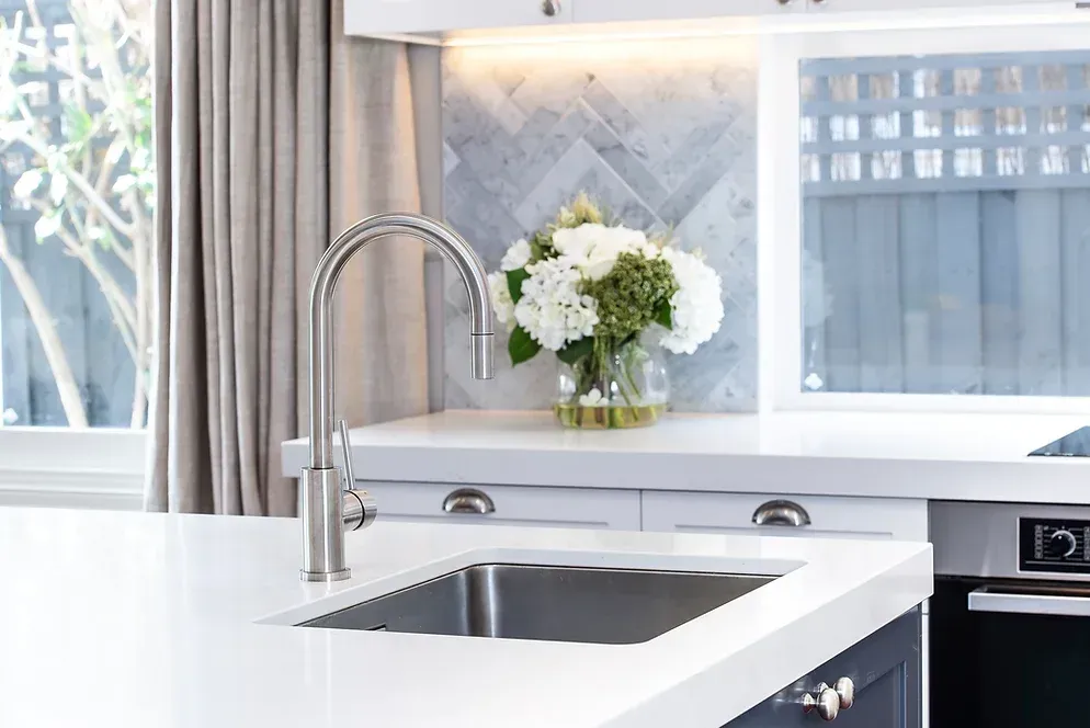 A kitchen sink with a vase of flowers on top of it.