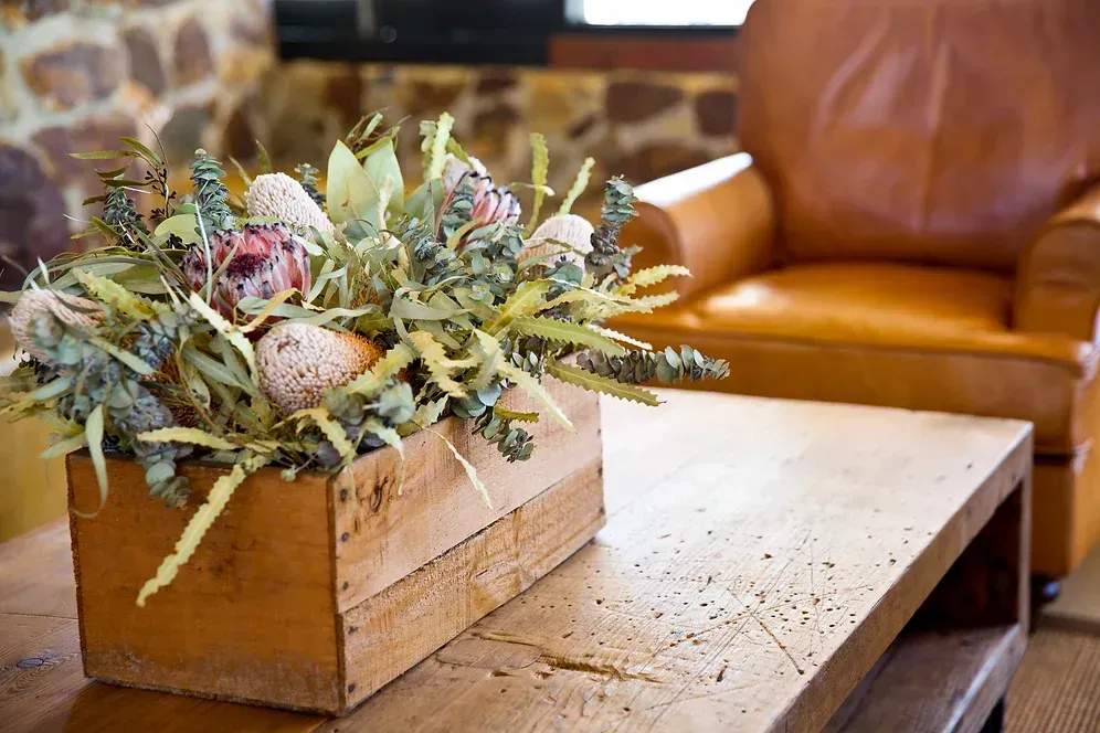 A wooden box filled with flowers is sitting on a wooden table.