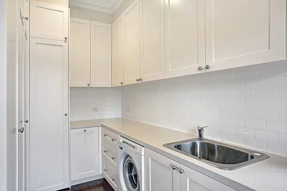 A laundry room with white cabinets, a washer and dryer, and a sink.