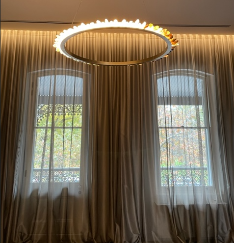 A room with two windows and a chandelier hanging from the ceiling