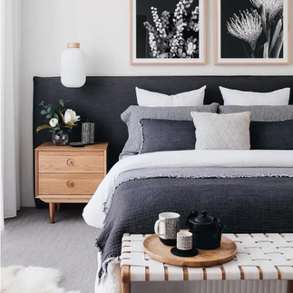 A bedroom with a bed a nightstand and a bench