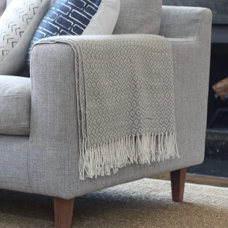 A grey couch with a blanket on the arm