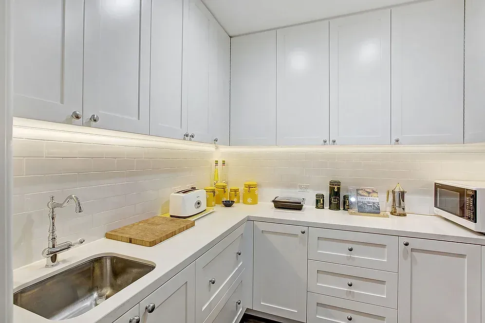 A kitchen with white cabinets, a sink, and a microwave.