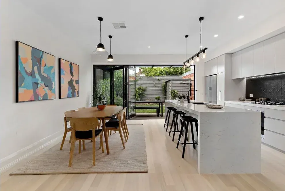 A kitchen and dining room in a house with a table and chairs.