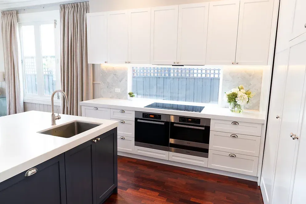 A kitchen with white cabinets, stainless steel appliances, a sink, and a large island.