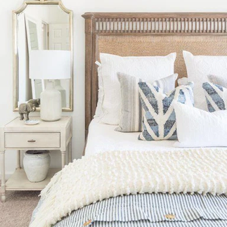 A bedroom with a bed, nightstand and mirror