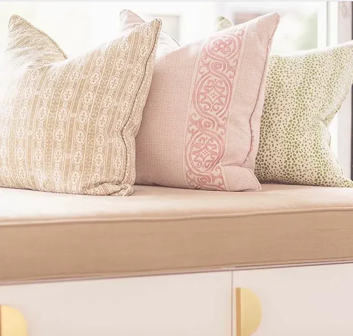Three pillows are sitting on a window seat next to a window.