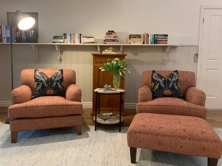 There are two chairs and an ottoman in the living room.
