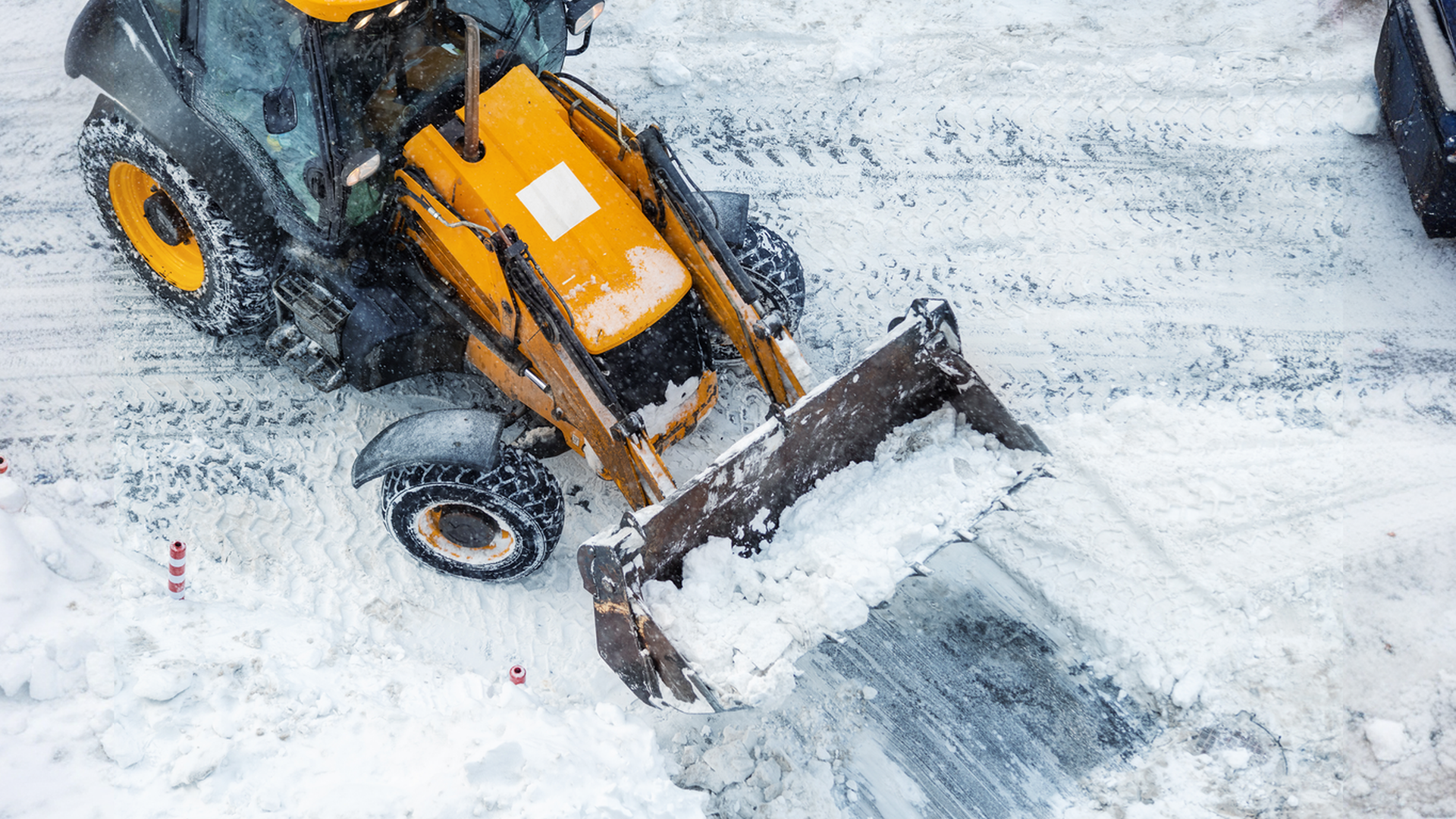 A yellow and black tractor is clearing snow from the ground.