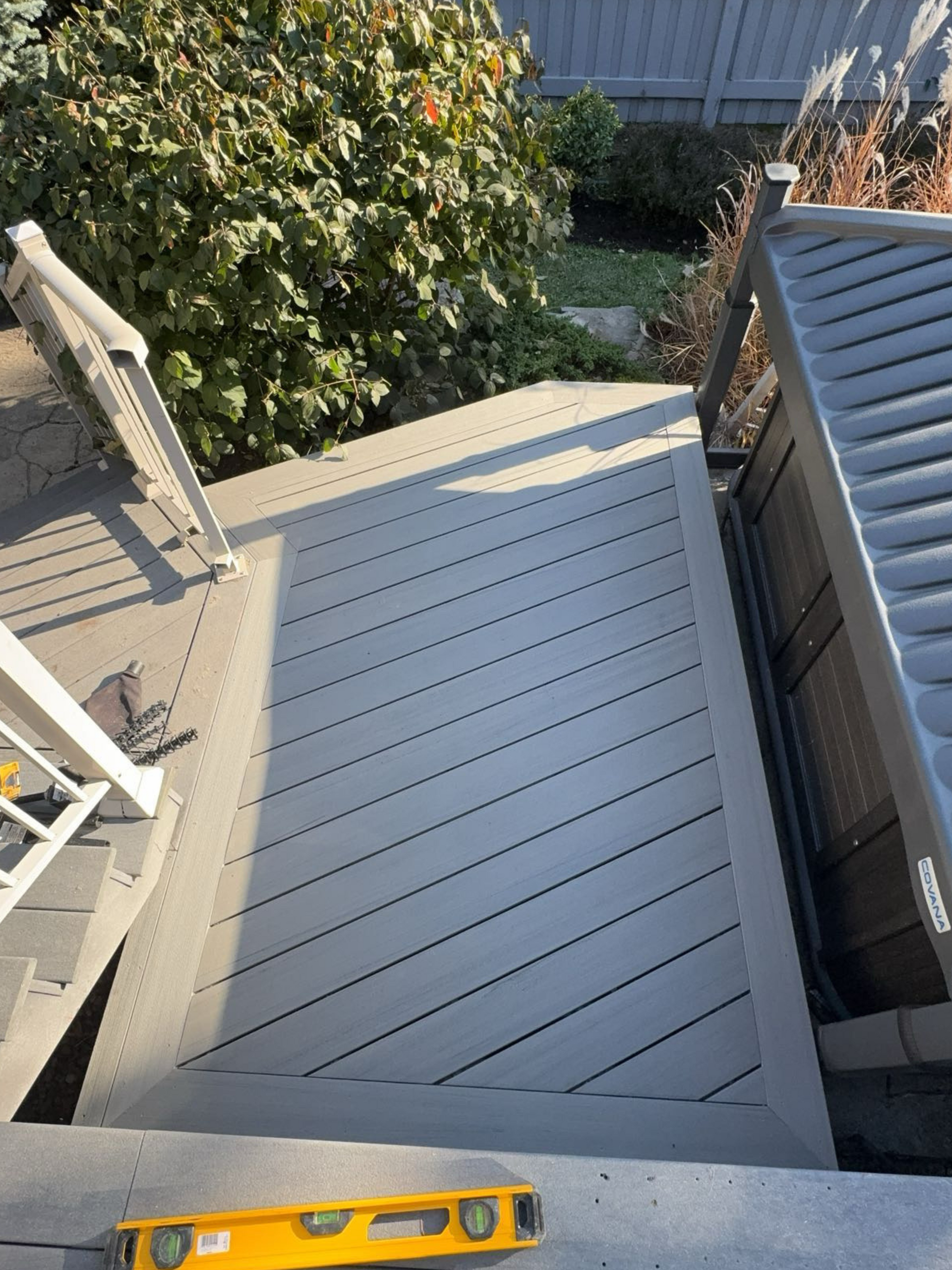 A yellow level is sitting on top of a wooden deck.