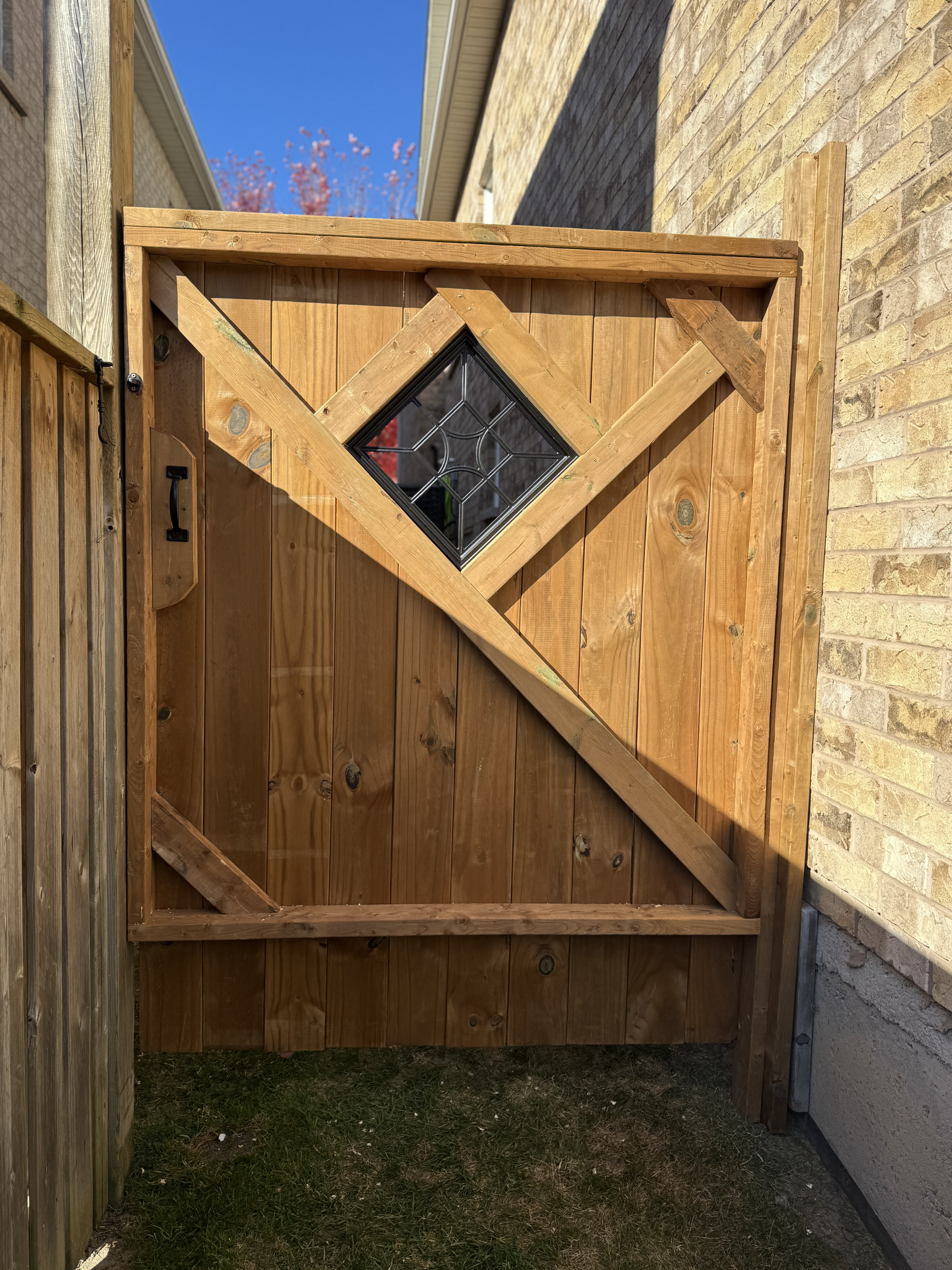 A wooden gate with a stained glass window in the middle of it.