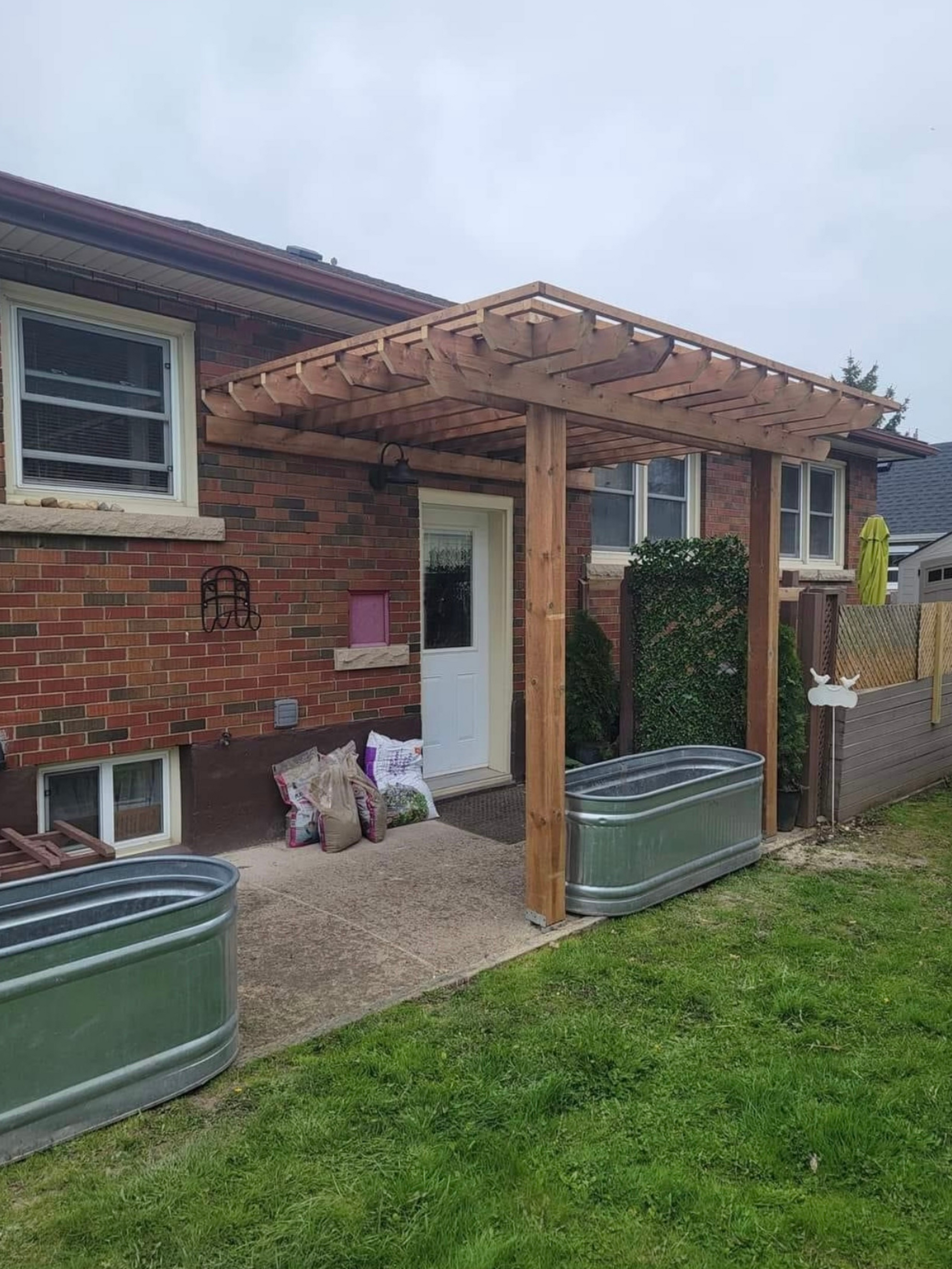 A brick house with a wooden pergola over the front door.