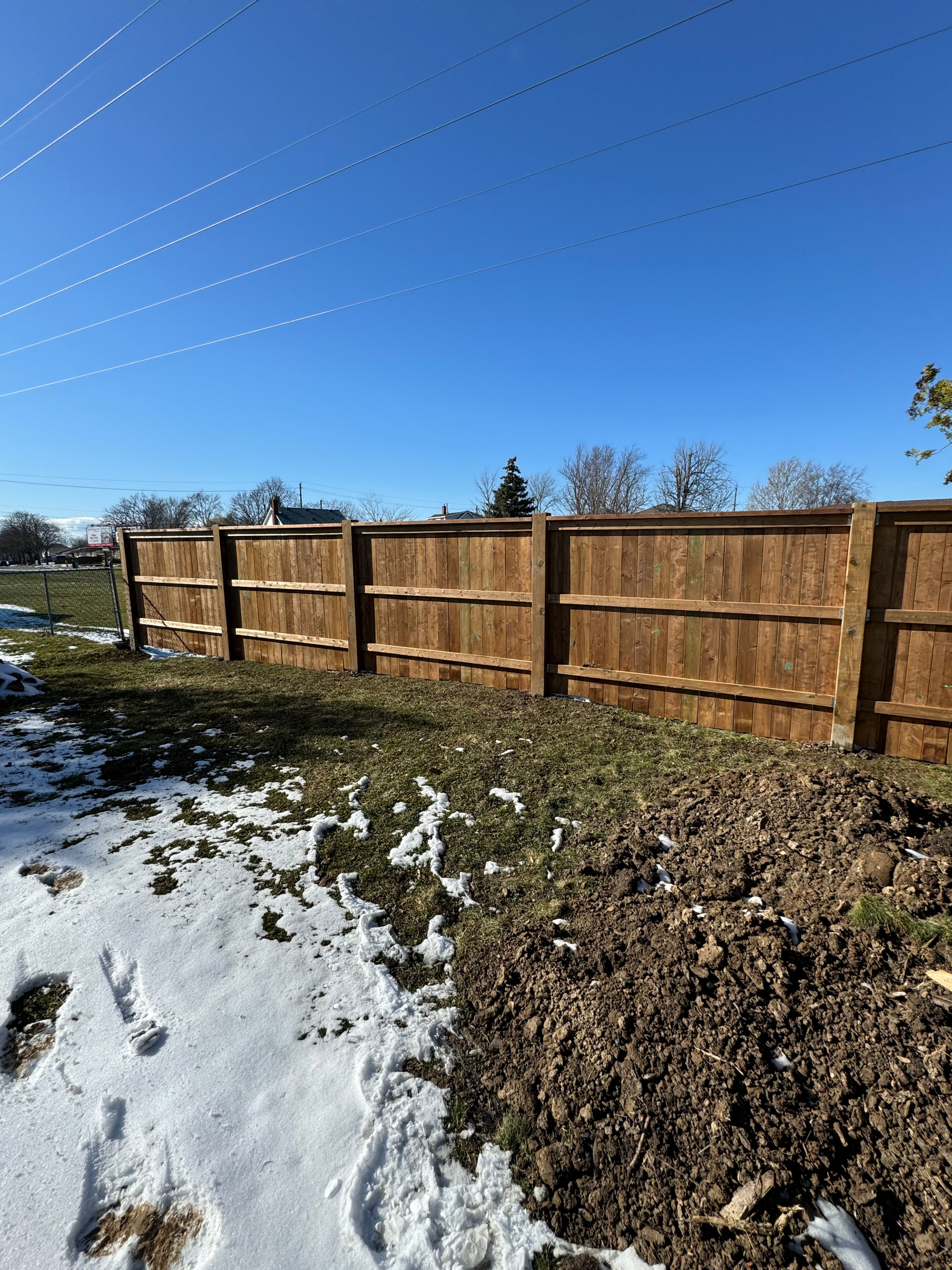 A wooden fence is in the middle of a snowy field.