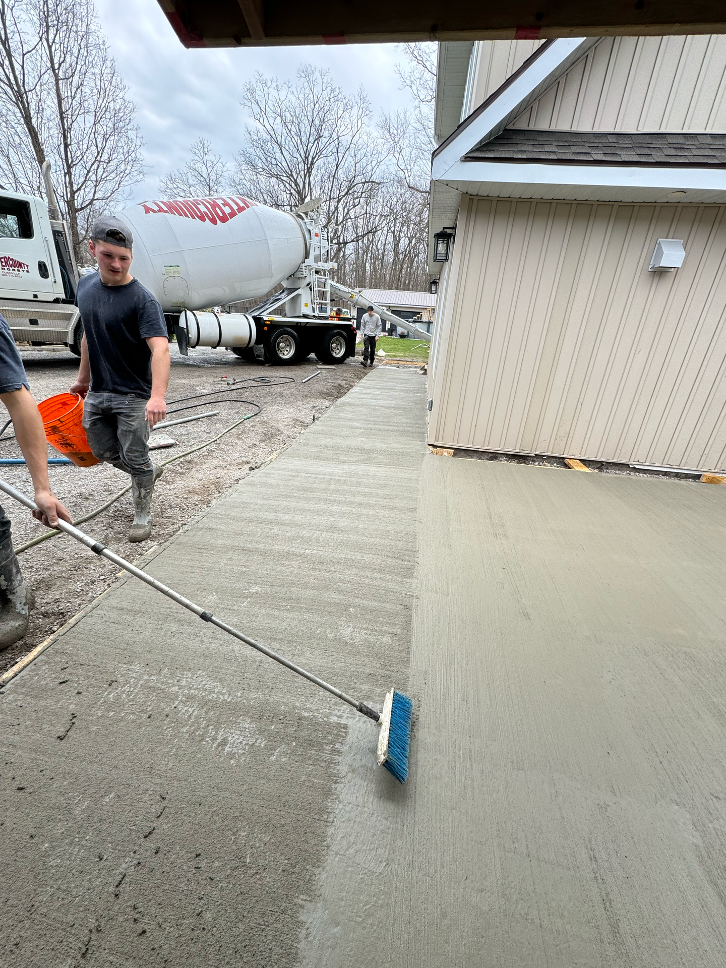 A man is using a broom to spread concrete on a sidewalk.