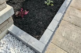 A garden with a brick border and white gravel next to a sidewalk.