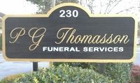 A dark brown, arch-top sign with gold lettering that reads, 