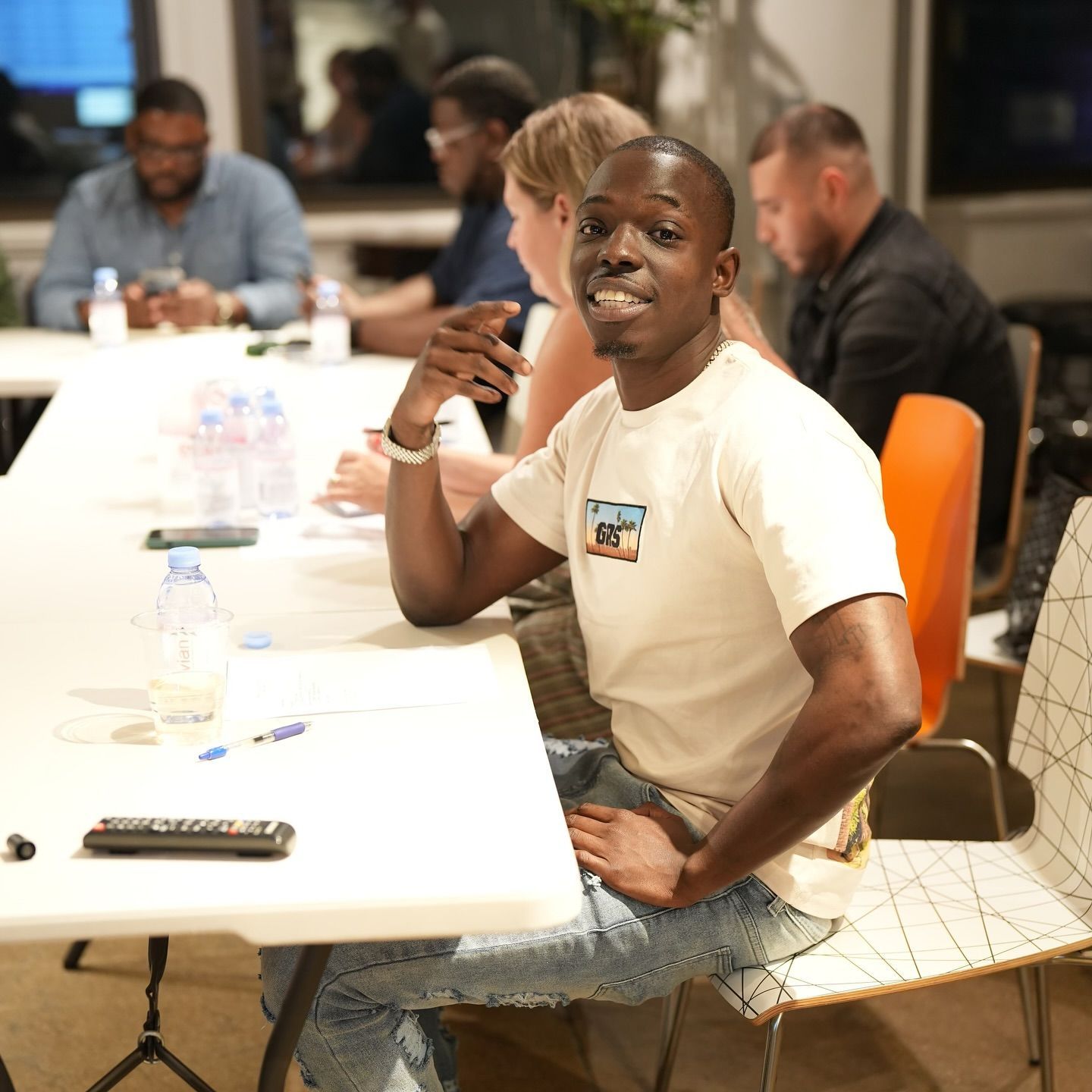 Ackquille in a white shirt is sitting at a table with other people