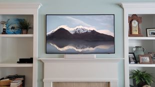 Samsung frame TV mounted above fireplace with built-in bookshelves. The TV has a soundbar also.