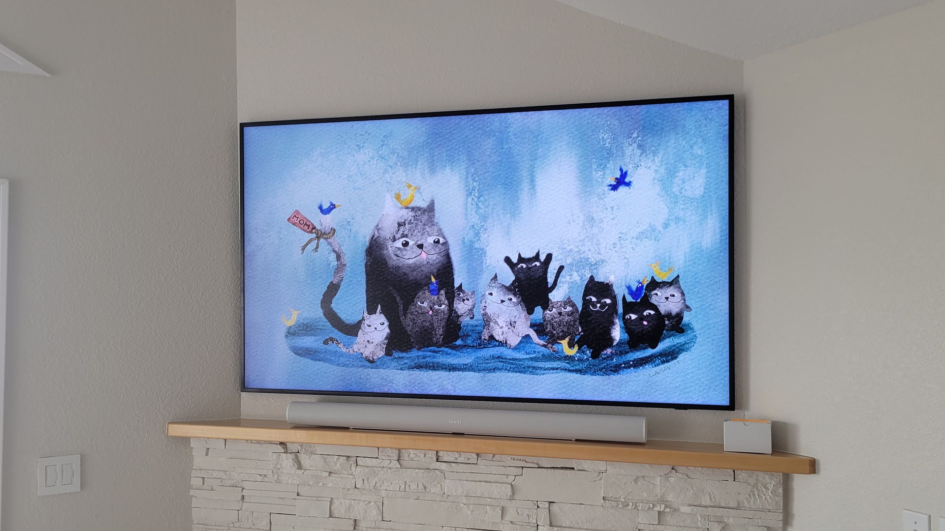 A samsung frame TV mounted above a fireplace with a sonos soundbar by fisher custom av.