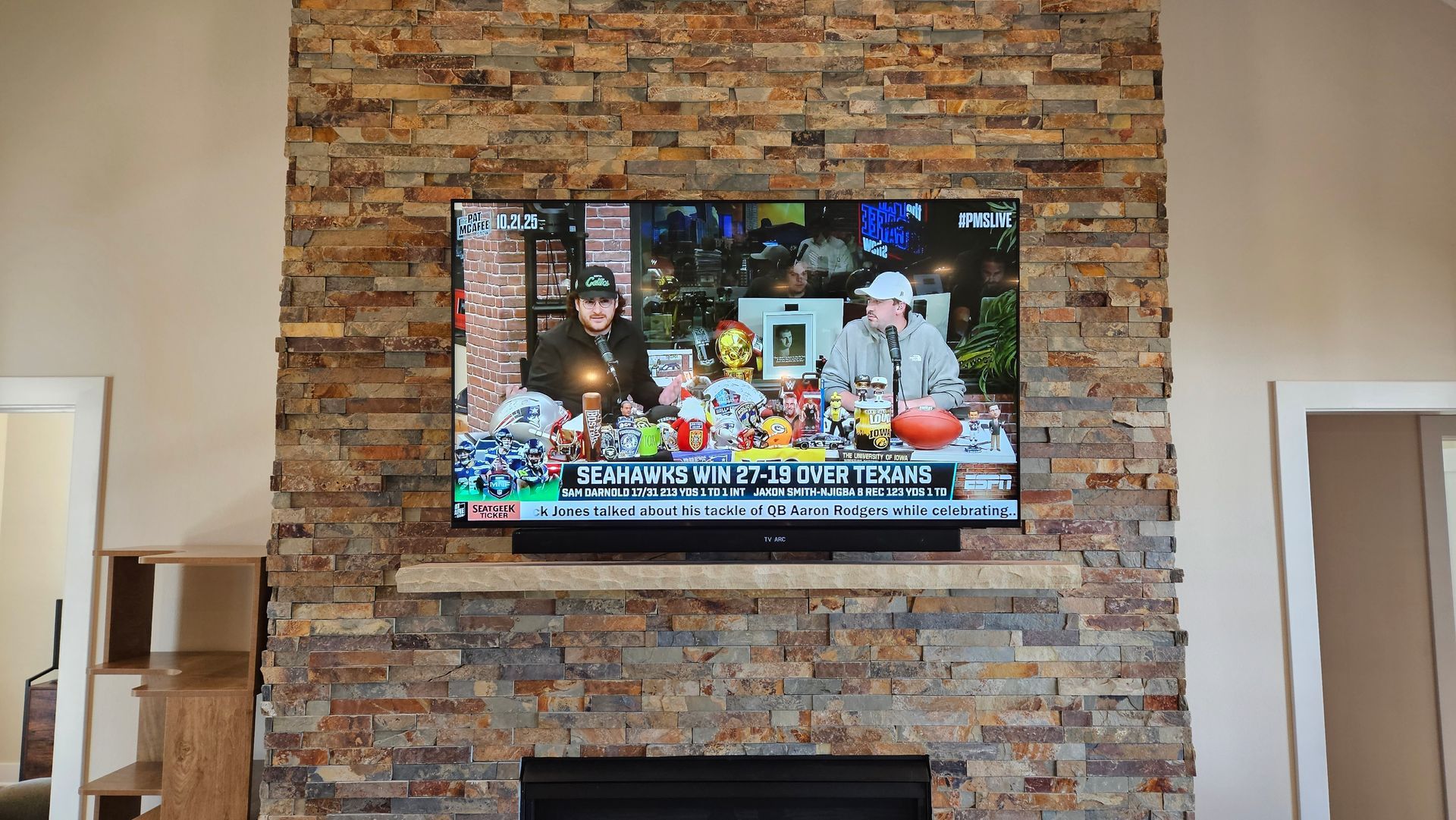TV and soundbar custom mounted on a stone fireplace by fisher custom av.