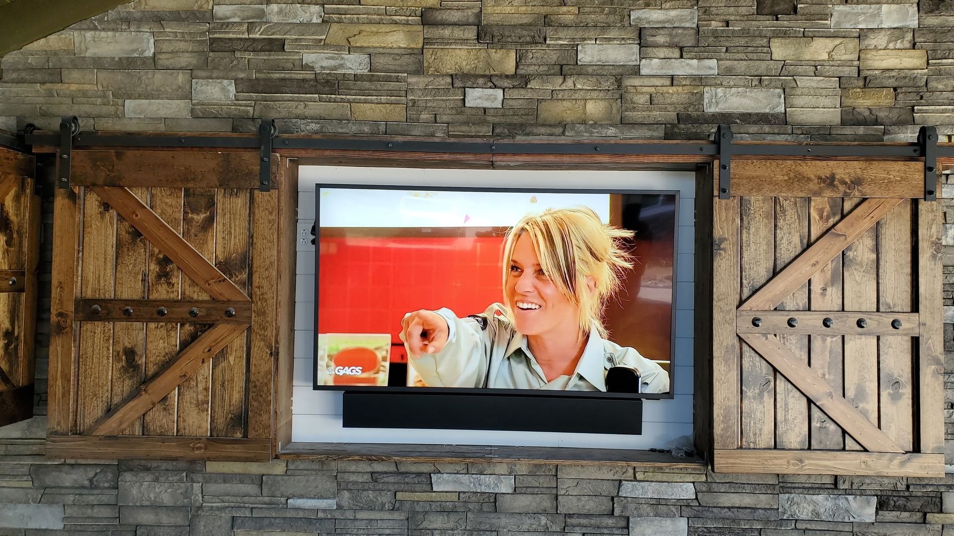 Outdoor TV custom mounted in a stone wall, by fisher custom av