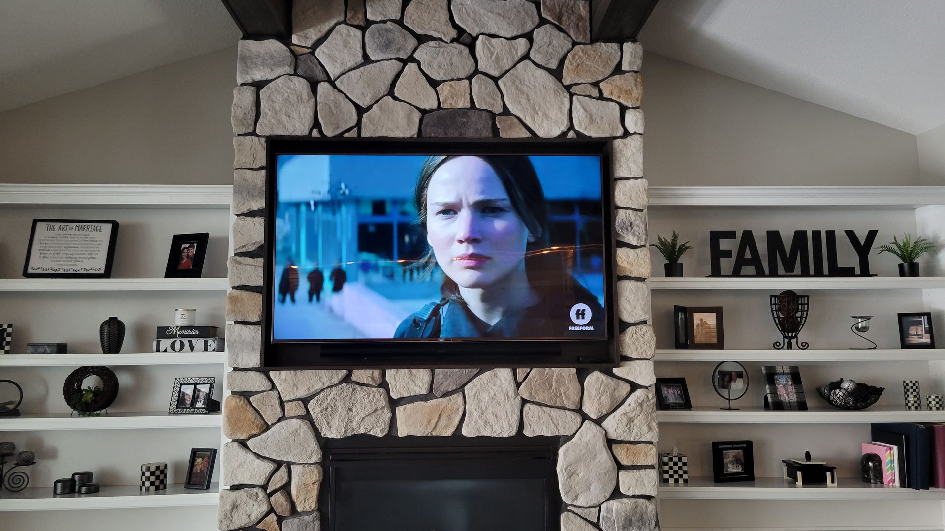 TV and soundbar custom mounted and recessed in a stone fireplace by fisher custom av.