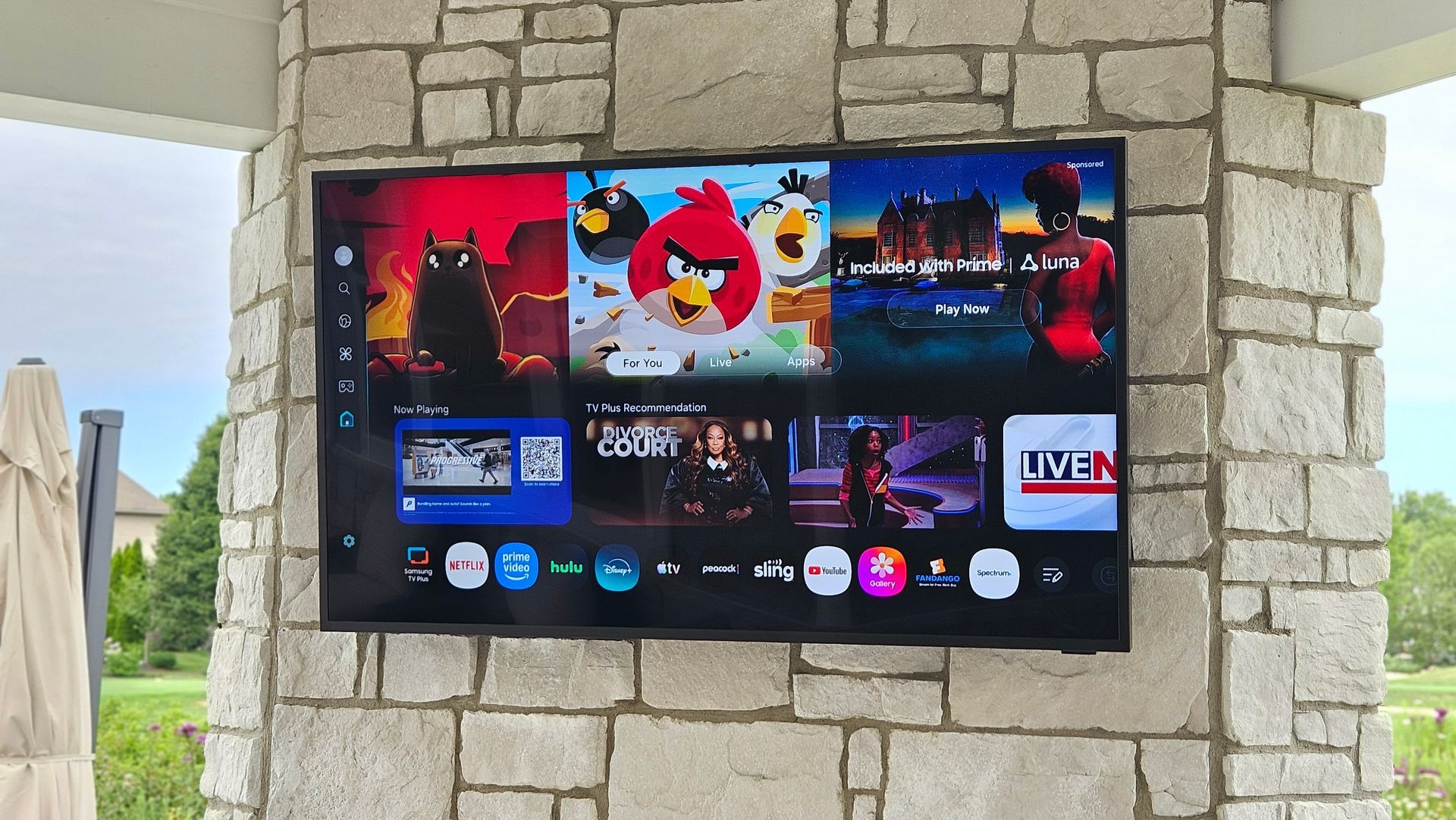 A samsung outdoor terrace tv mounted on a brick stone wall above a fireplace by fisher custom av in north central ohio