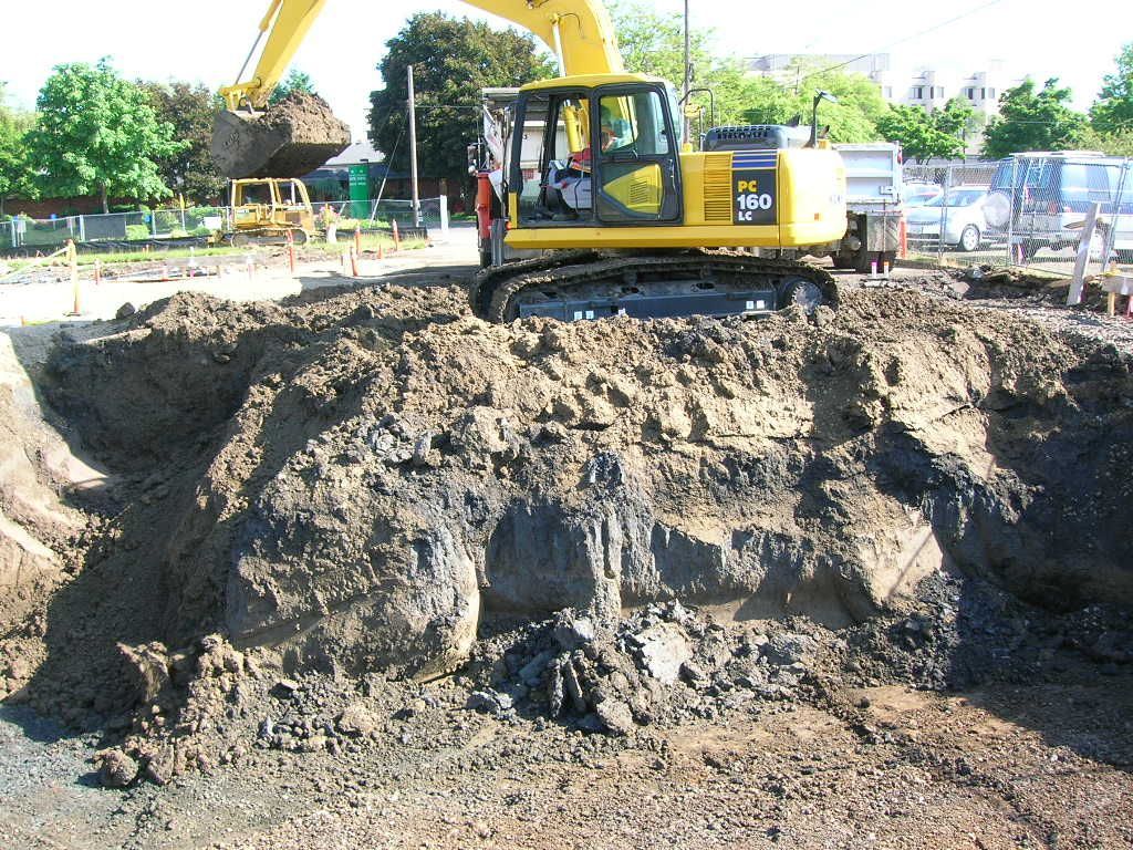 A Yellow Excavator On A Dirt Mound — Eugene, OR — Emerald Excavating A Yellow Excavator On A Dirt Mound — Eugene, OR — Emerald Excavating