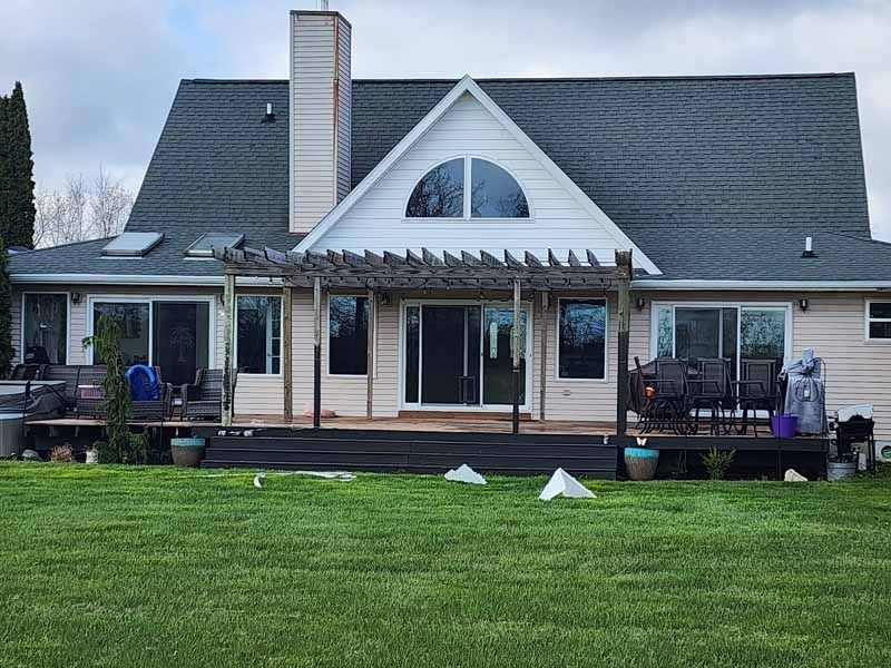 The back of a house with a large lawn in front of it.