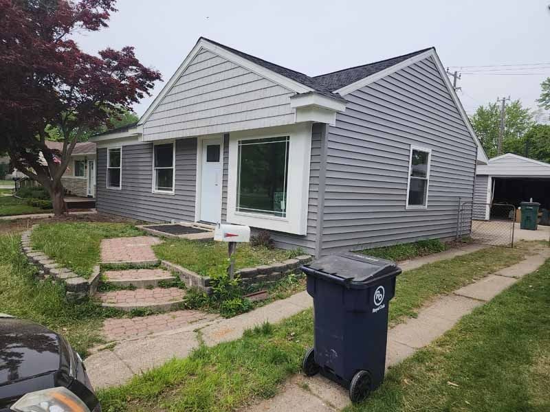 A house with a trash can in front of it.
