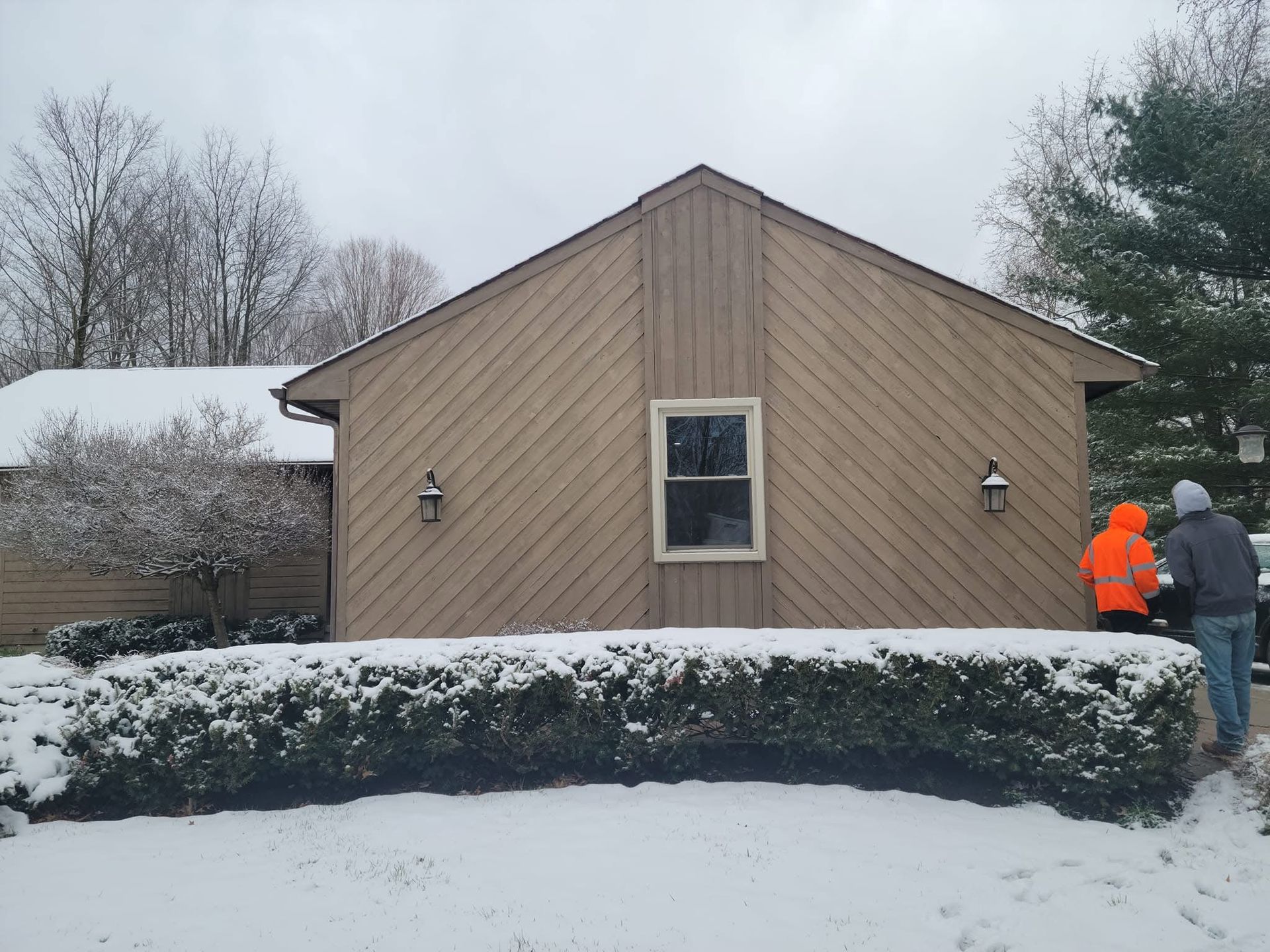 Building under construction with white siding and dark roof, leaves on the ground.