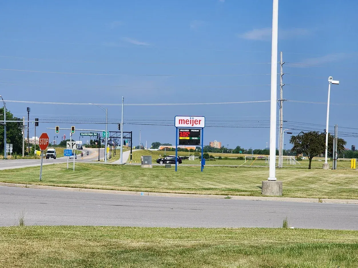 Meijer store sign by a roadside intersection on a sunny day