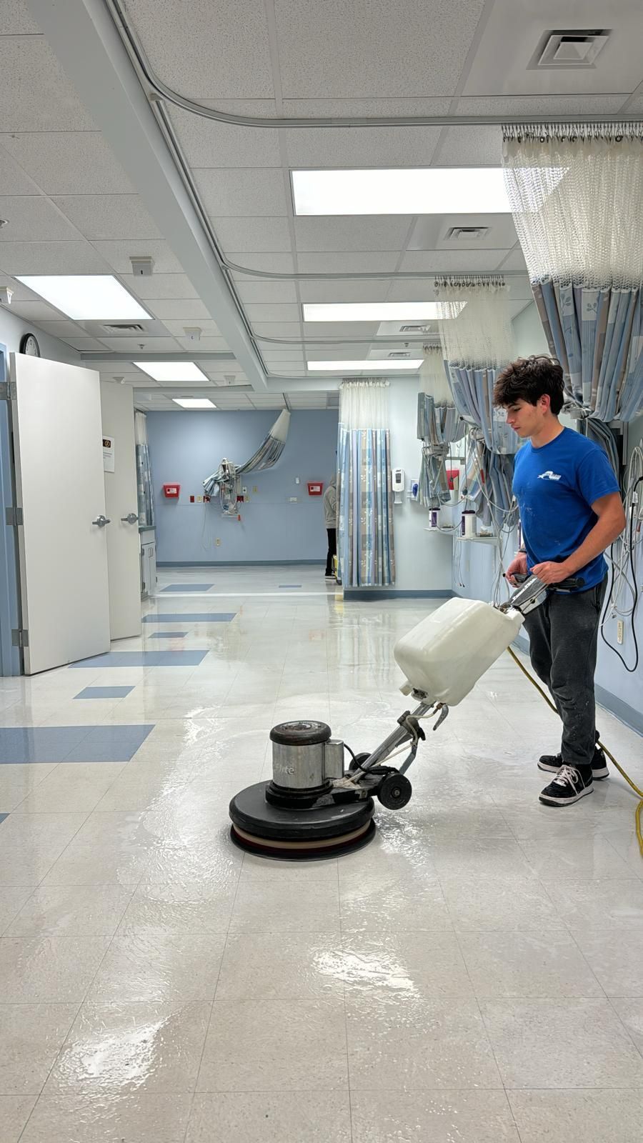 A man is cleaning the floor of a building with a machine.