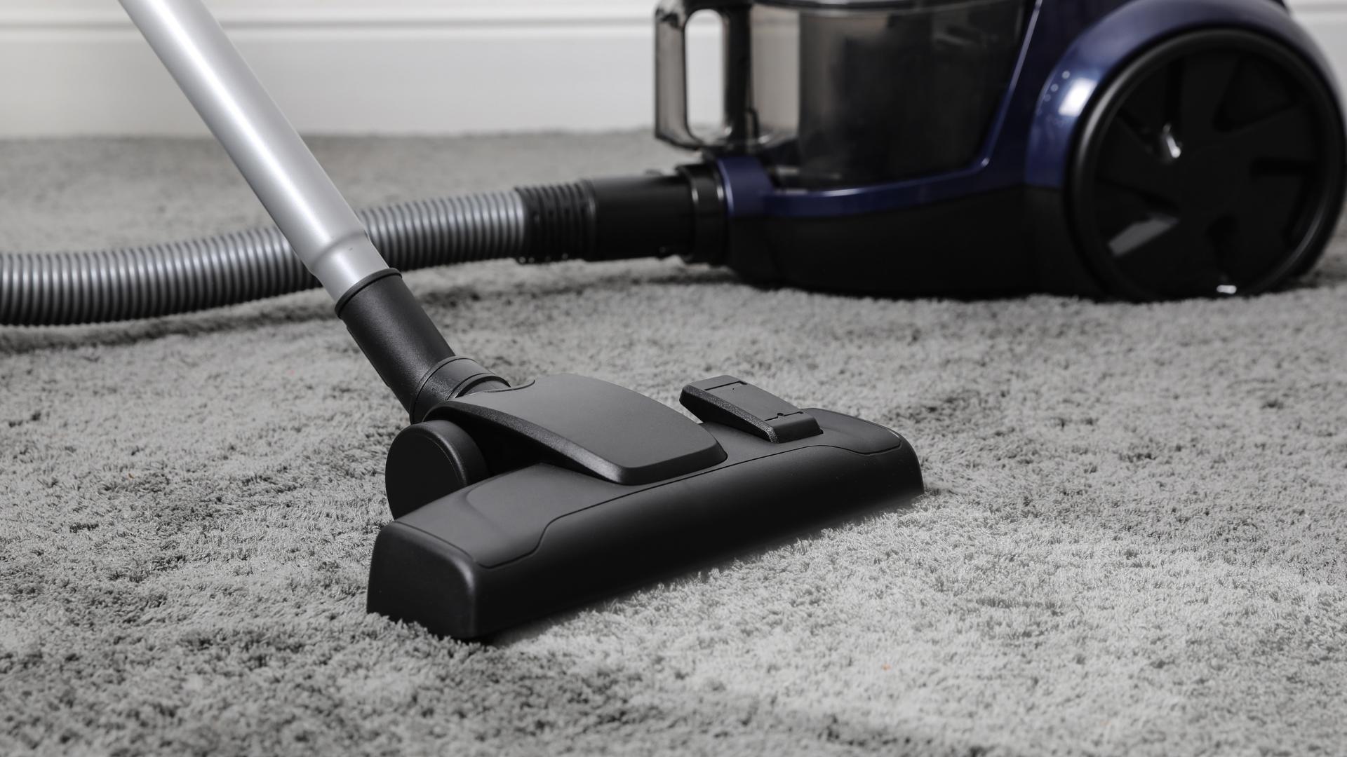 A vacuum cleaner is being used to clean a carpet.