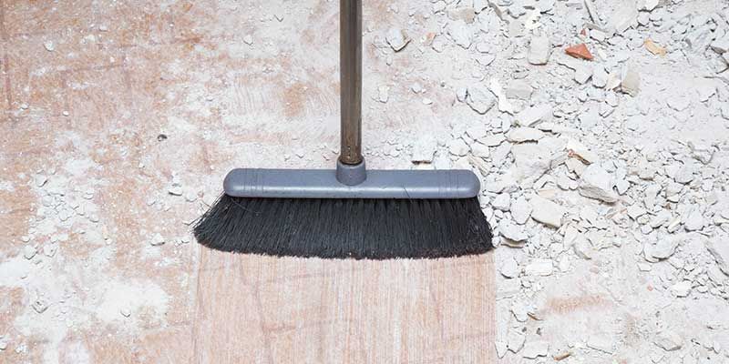 A broom is sitting on top of a wooden floor.