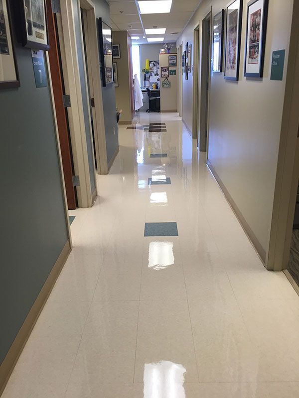 A long hallway in a hospital with a white tile floor