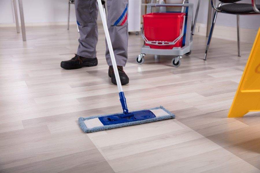 A man is cleaning the floor with a mop.