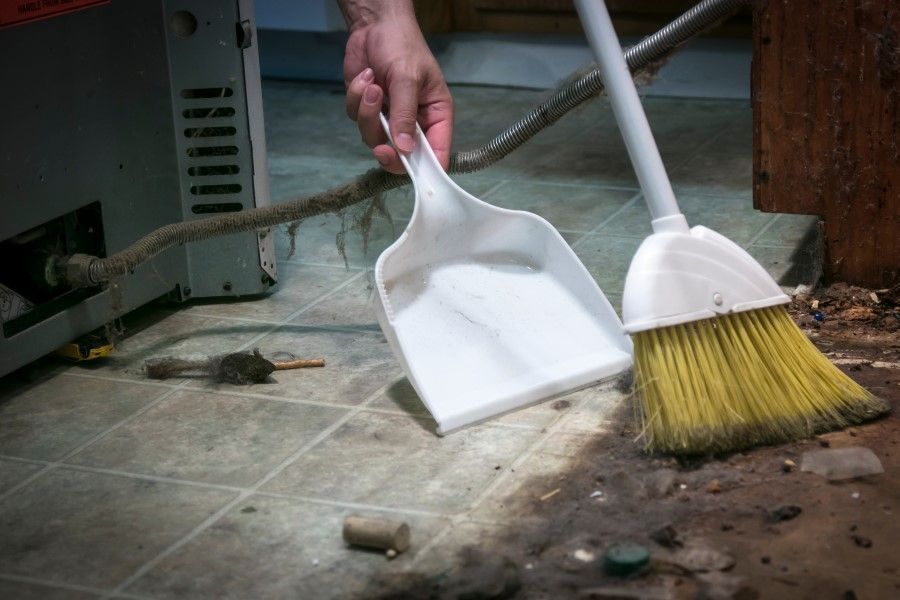A person is sweeping the floor with a broom and scoop.
