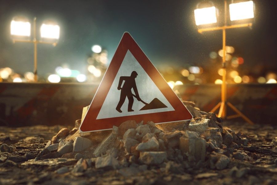 A construction sign is sitting on top of a pile of rocks.