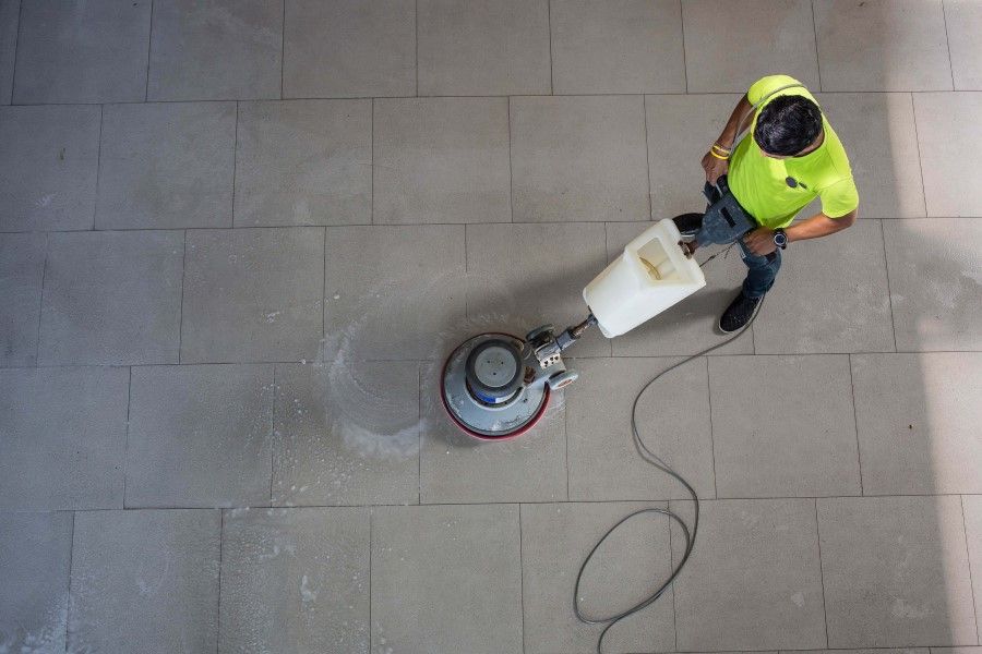 A man is cleaning a tiled floor with a machine.