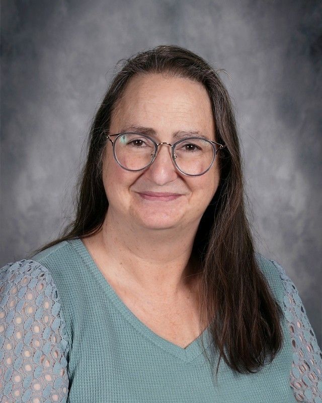 Woman with glasses and a floral shirt smiling.