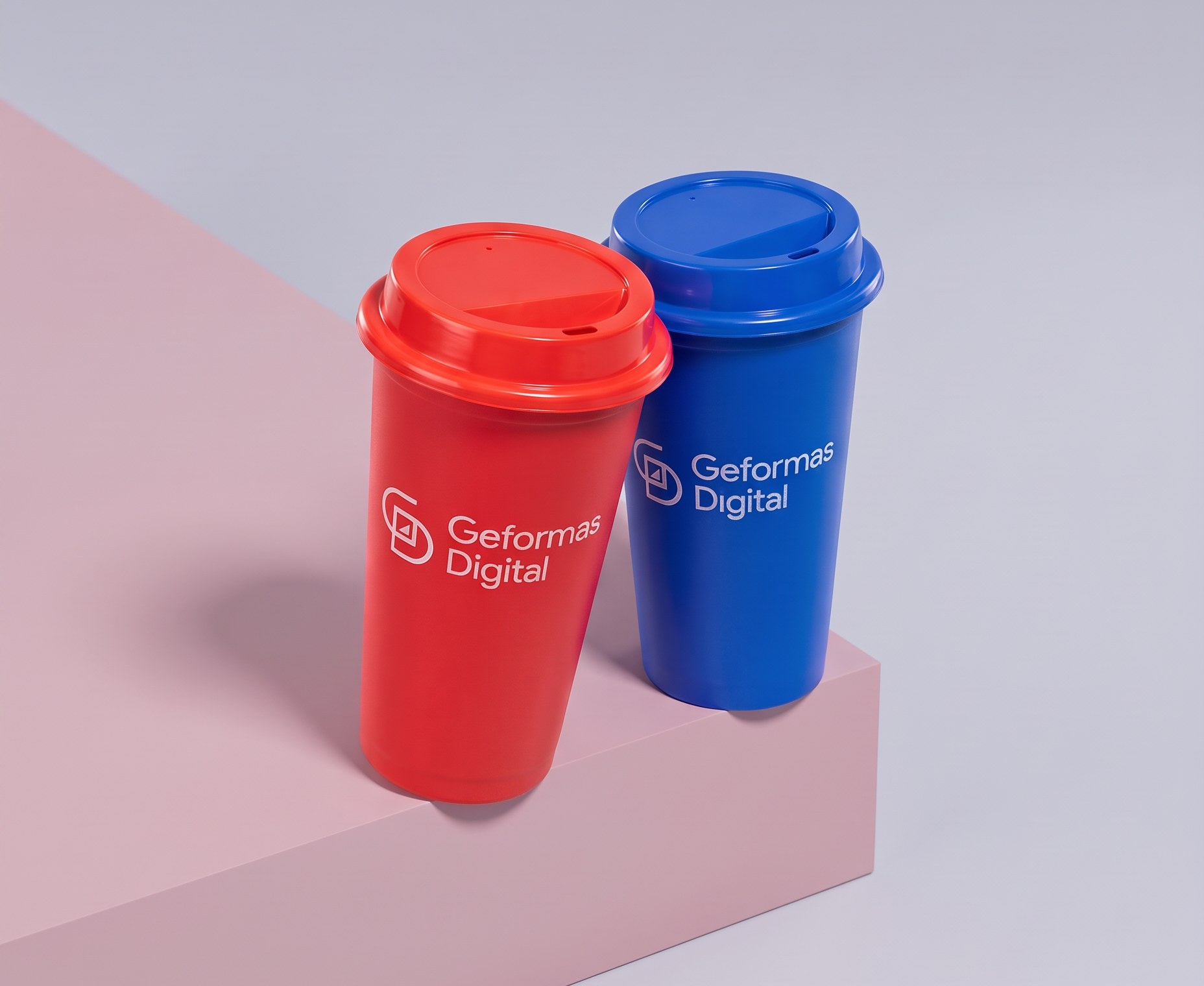 Dos vasos de plástico promocionales de Geformas, uno rojo y uno azul, sobre una repisa rosa contra un fondo claro.