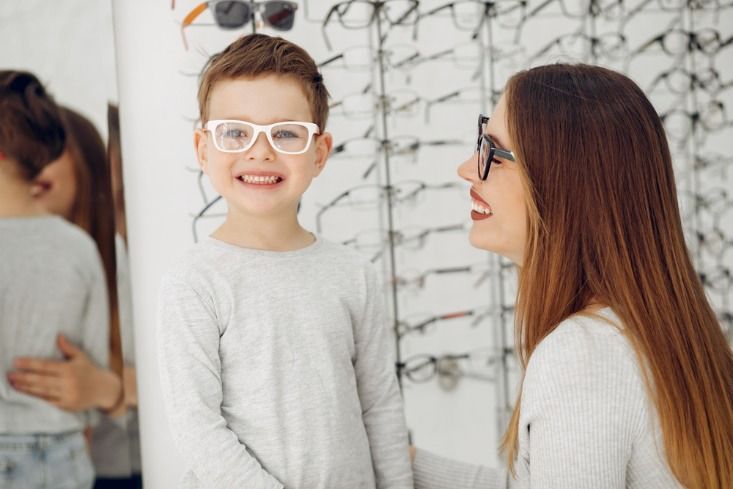 Una mujer y un niño se prueban gafas en una óptica.