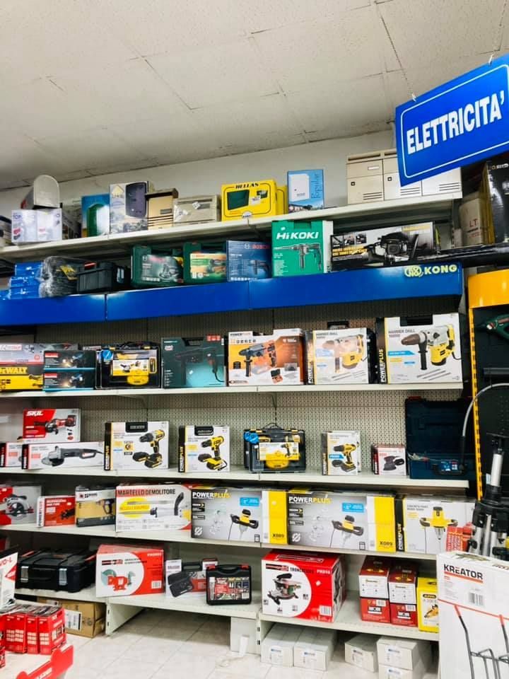 Scaffali pieni di utensili elettrici imballati in un negozio; cartello blu 