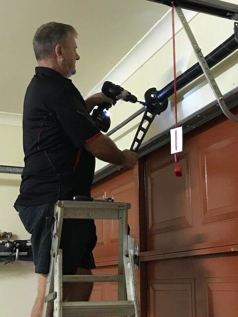 Contractor Repairing Tension Lifts — Garage Door Maintenance in Gold Coast