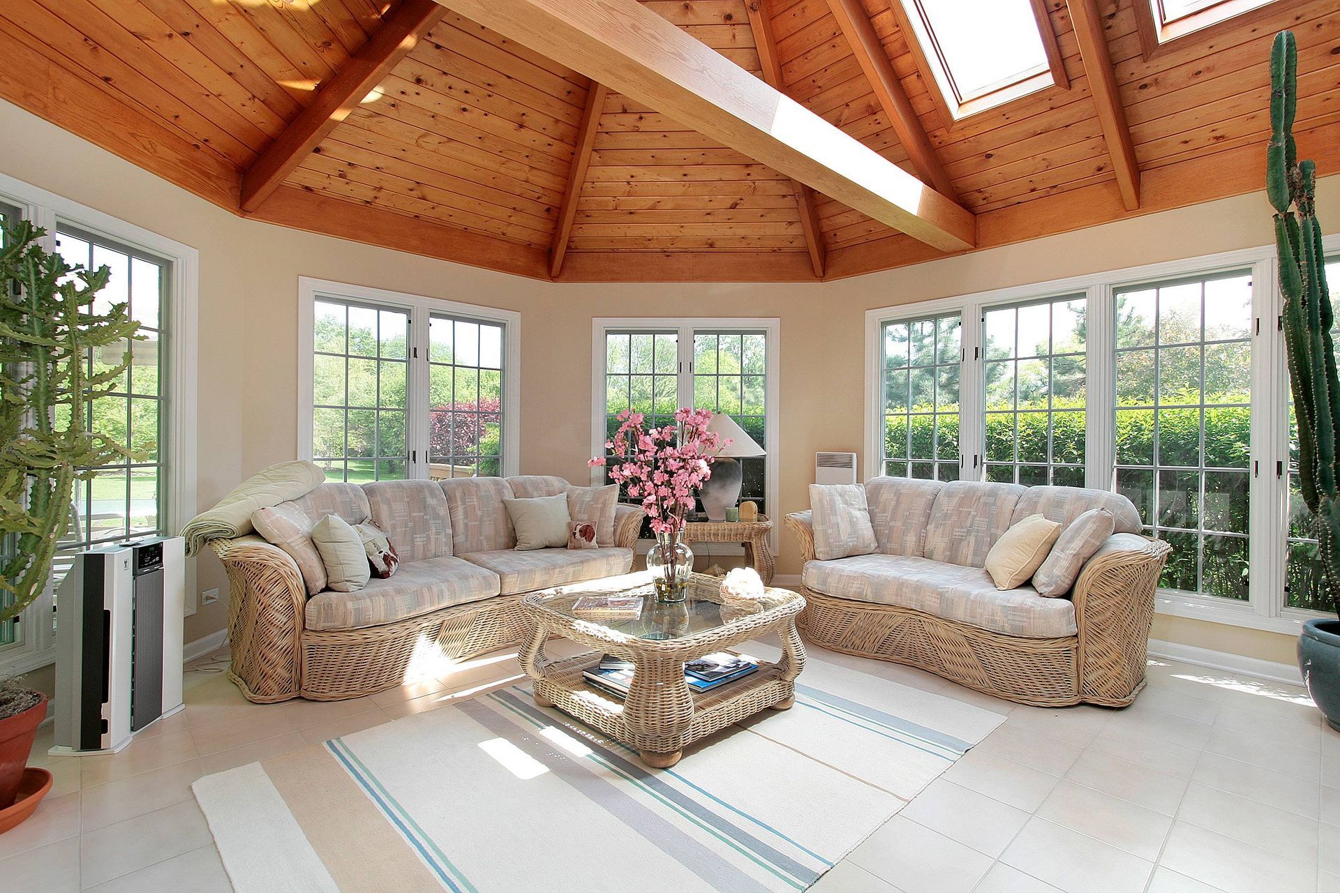 Sunroom with gray wicker couches around a table with a vase full of pink flowers near at The Blind G