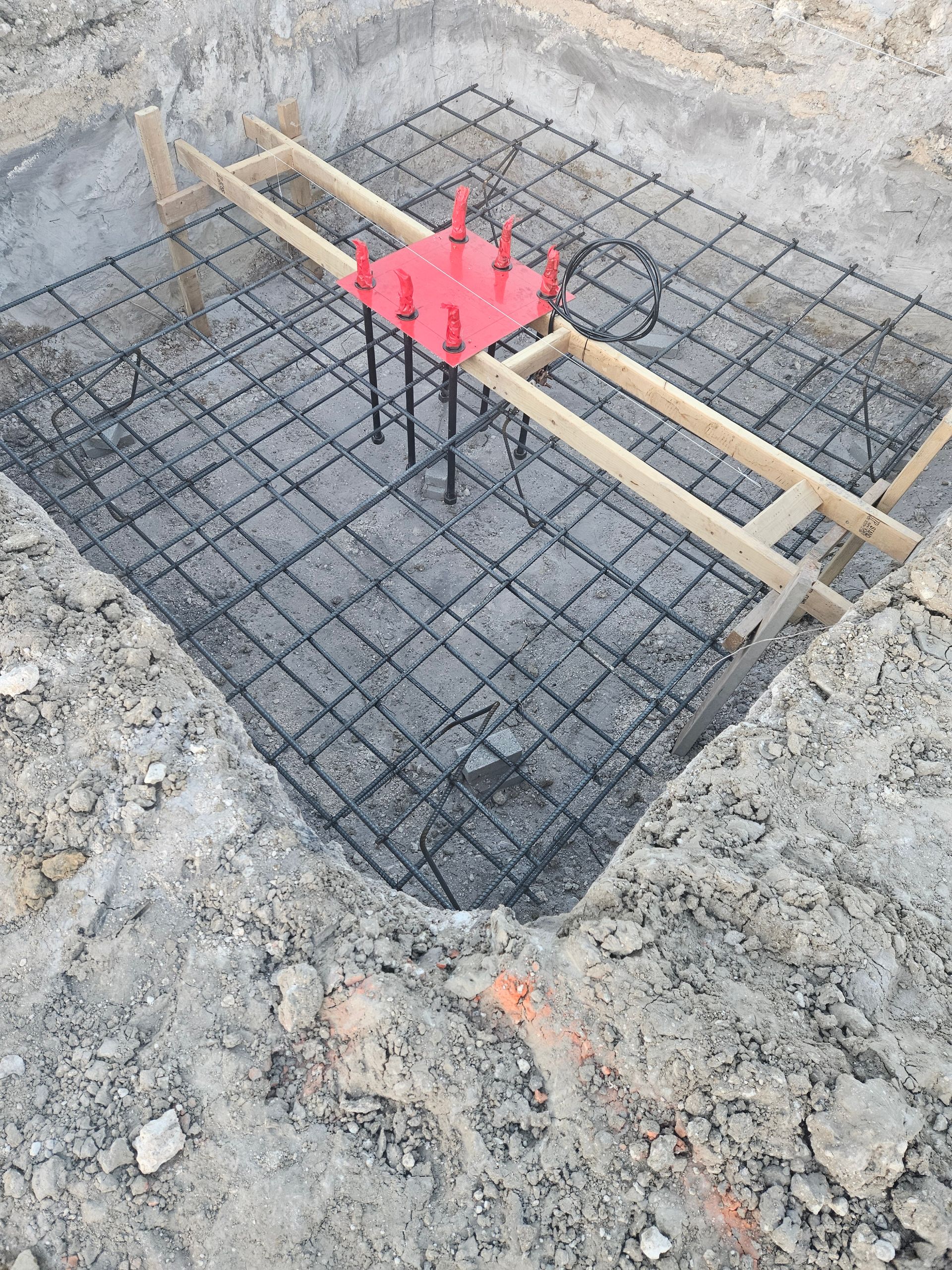 A bunch of metal rods are sitting in the dirt on a construction site.